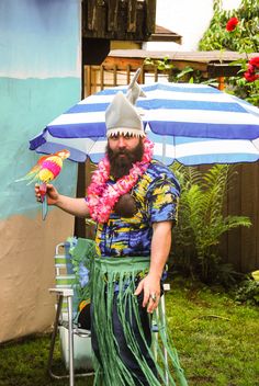 a man sitting in a lawn chair with a bird on his hand and an umbrella over his head