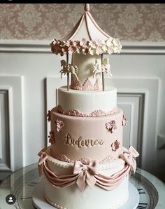 a pink and white cake with a carousel on top