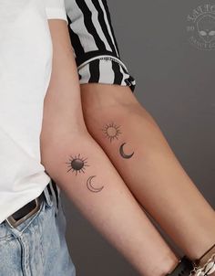 two people with matching tattoos on their arms, one holding the other's arm