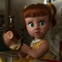 a close up of a doll looking at its own reflection in a mirror with another doll behind it