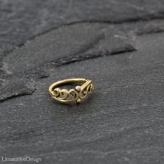 a gold ring sitting on top of a black stone surface with the word love written in cursive writing