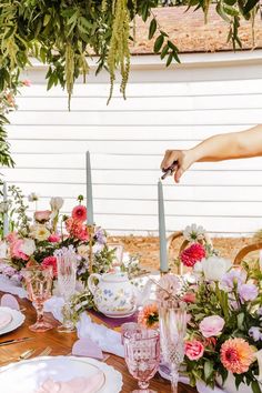 a table is set with pink and white flowers, candles, plates and napkins