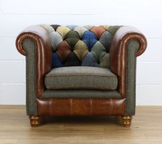 a brown leather chair sitting on top of a hard wood floor next to a white brick wall