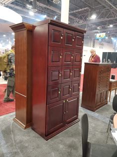 a room filled with lots of wooden furniture and people sitting at desks in the background