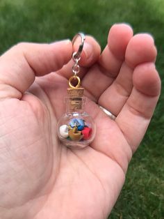 a hand holding a tiny glass bottle with charms in it