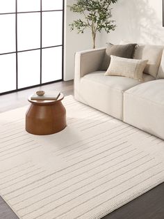 a living room with a white couch and wooden coffee table on top of the rug