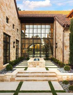 an outdoor courtyard with stone walls and steps leading up to the front door, surrounded by grass