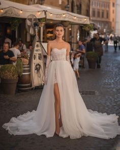 a woman in a wedding dress standing on the street