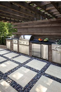 an outdoor kitchen with stainless steel appliances and stone flooring