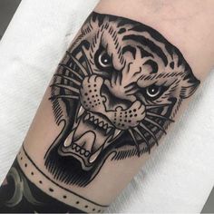 a black and white tiger tattoo on the left arm with an eye patch in it's center