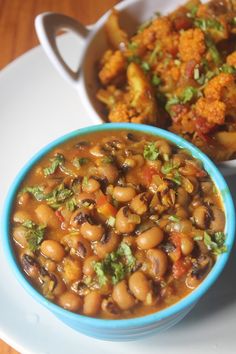 two bowls filled with beans and broccoli on top of a white saucer