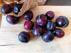 plums on a cutting board next to a paper bag