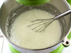 a mixing bowl filled with batter on top of a green stove burner next to a whisk