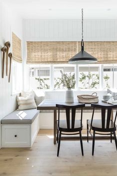 a dining room table with four chairs and a bench in front of the window,