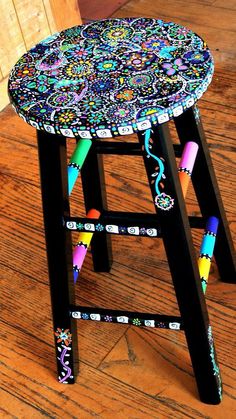 a colorful stool sitting on top of a wooden floor