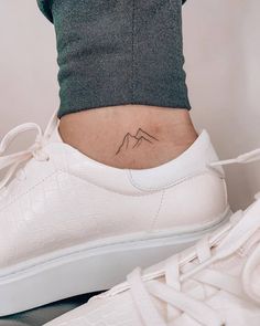 a woman's foot with a small mountain tattoo on her lower back side view