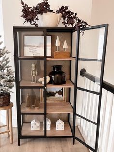 an open book case filled with lots of books next to a christmas tree and potted plant