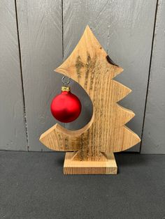 a wooden christmas tree with a red ornament hanging from it's center