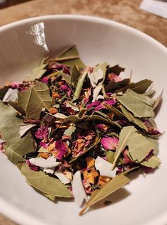 a white bowl filled with flowers and leaves