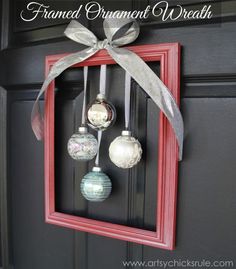 a red frame with ornaments hanging from it's side and a bow on the front door