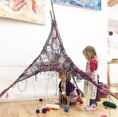 two children playing with art in an art studio, one is holding the string on top of the sculpture