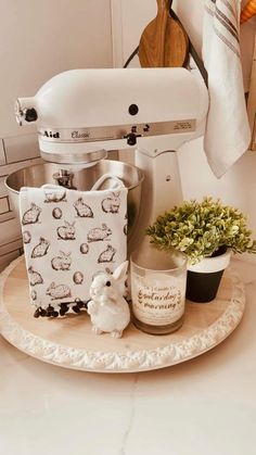 a white mixer sitting on top of a kitchen counter next to a potted plant