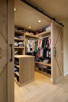 an open closet with wooden doors and clothes hanging on the shelves in front of it