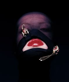 a woman with red lips and piercings on her nose wearing a black veil over her head