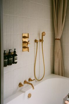 a bath tub sitting under a window next to a shower head and faucet