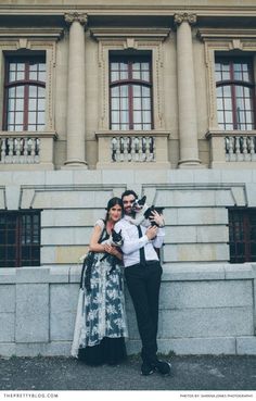 a man and woman standing next to each other in front of a building with columns