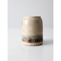 a white vase with blue and brown designs on the outside, sitting on a table