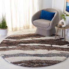 a living room area with a chair, rug and potted plant on the floor