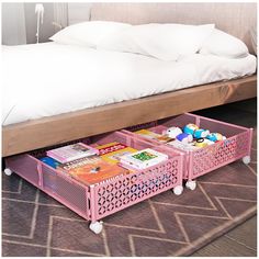 a bed with two pink baskets under it on the floor next to a white pillow