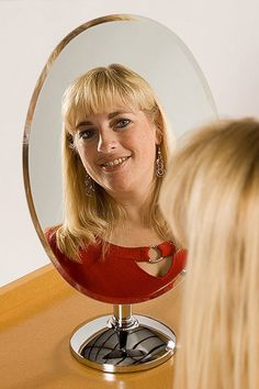 a woman looking at herself in the mirror with her hair pulled back and blonde hair