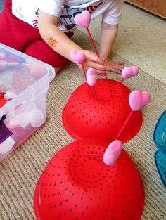 a young child sitting on the floor playing with some balls and sticks in front of her