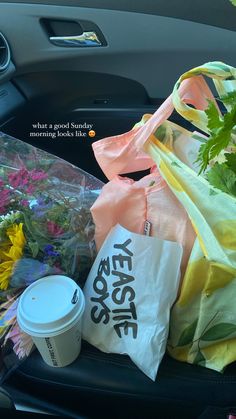 flowers and bags are sitting in the back seat of a car, next to a starbucks cup