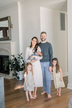 a man, woman and two children standing in a living room with hardwood flooring