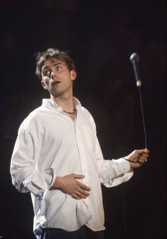 a man standing in front of a microphone with his hand on the mic and looking up