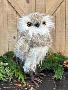 a stuffed owl sitting on top of green plants