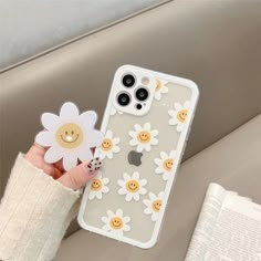 a person holding up a phone case with a flower on the front and smiley face on the back