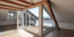 an empty room with wooden floors and large glass windows on the wall, overlooking mountains