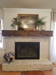 a living room with a fire place and some plants on top of the mantel