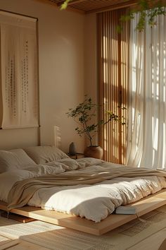 a large bed sitting under a window next to a wooden table with a potted plant on it