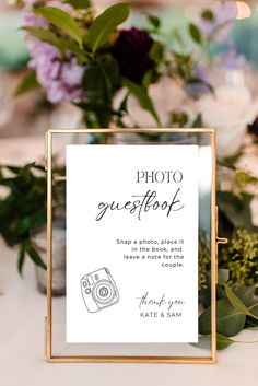 a photo guest sign sitting on top of a table next to purple and green flowers