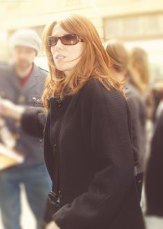 a woman wearing sunglasses standing next to other people