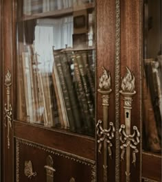 an old book case with many books in it's glass front door and ornate carvings on the doors