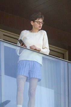 a woman standing on top of a balcony next to a window