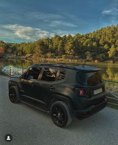 a black jeep parked on the side of a road next to a body of water