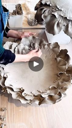 a person sitting on the floor working on a piece of art that looks like oysters