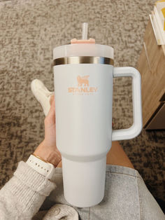 a person holding a white travel mug in their hand